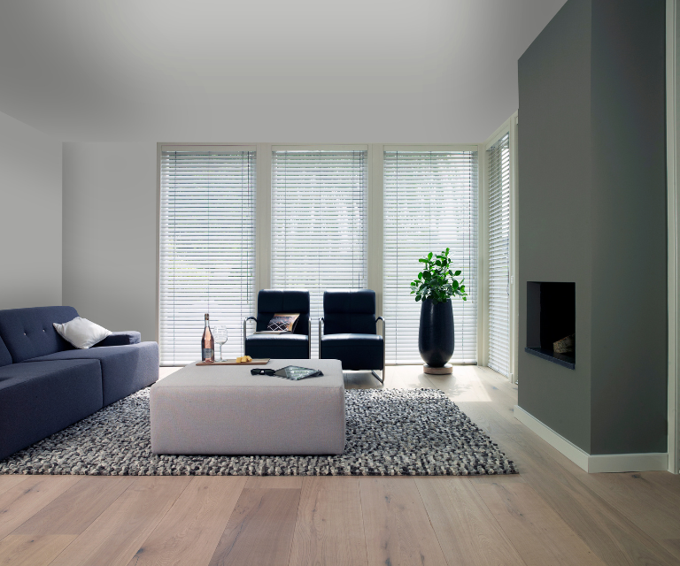 Houten jaloezieën in modern interieur met zacht vloerkleed en grijze accentmuur