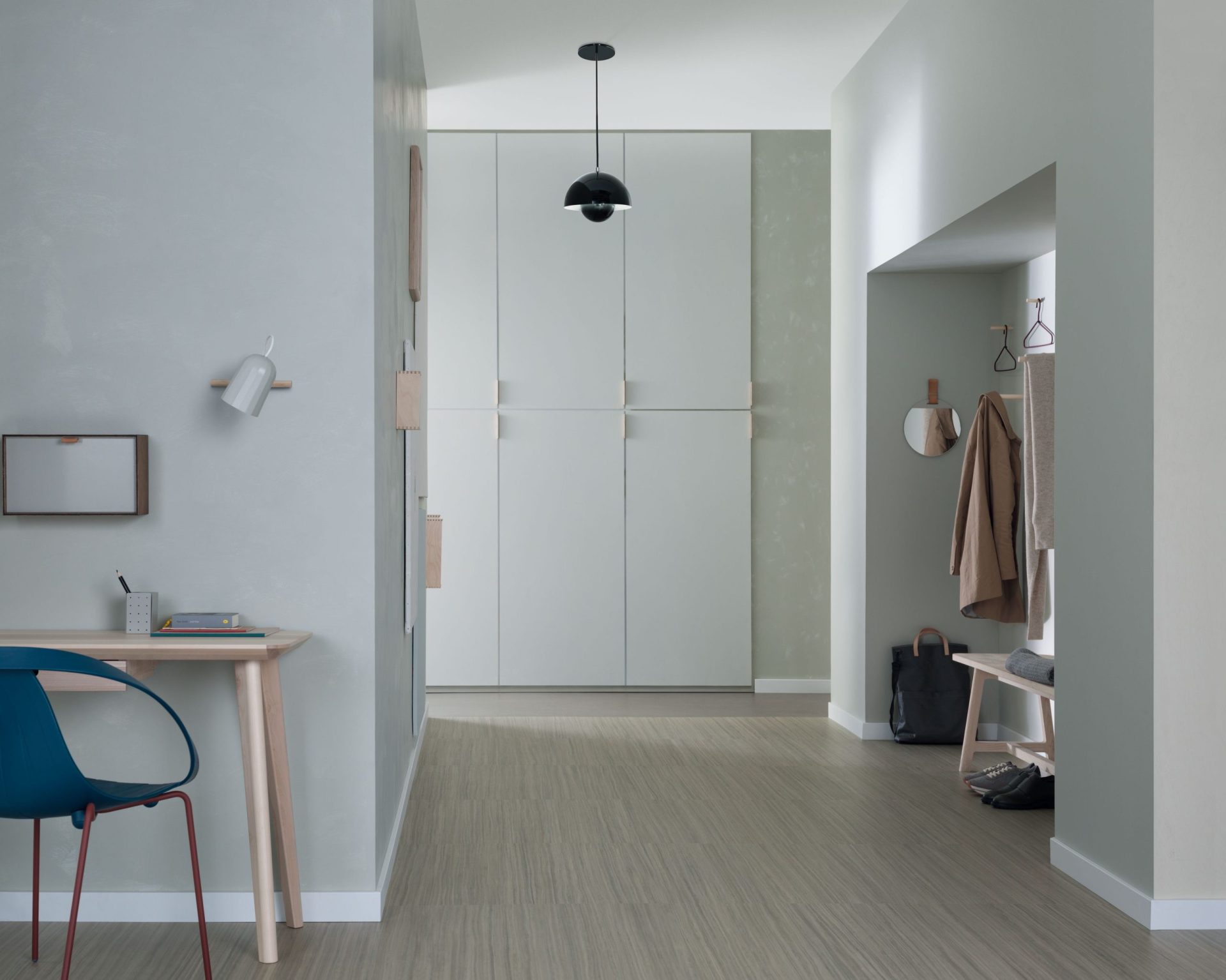 Ruime hal met witte wandkasten, garderobe in een nis en houtlook Marmoleum vloer.