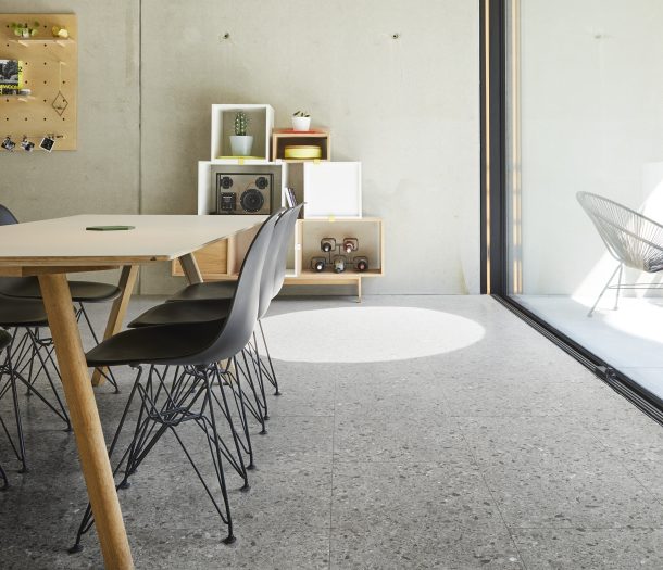 Woonkeuken met tegelvloer graniet look, houten 6persoons tafel en industriele stijl stoelen.