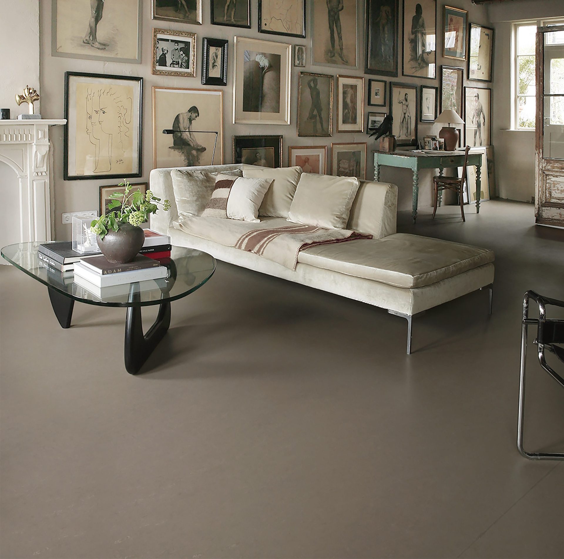 Moderne woonkamer met donkergrijze marmoleum vloer, glazen salontafel, beige bank en kunst aan de muur