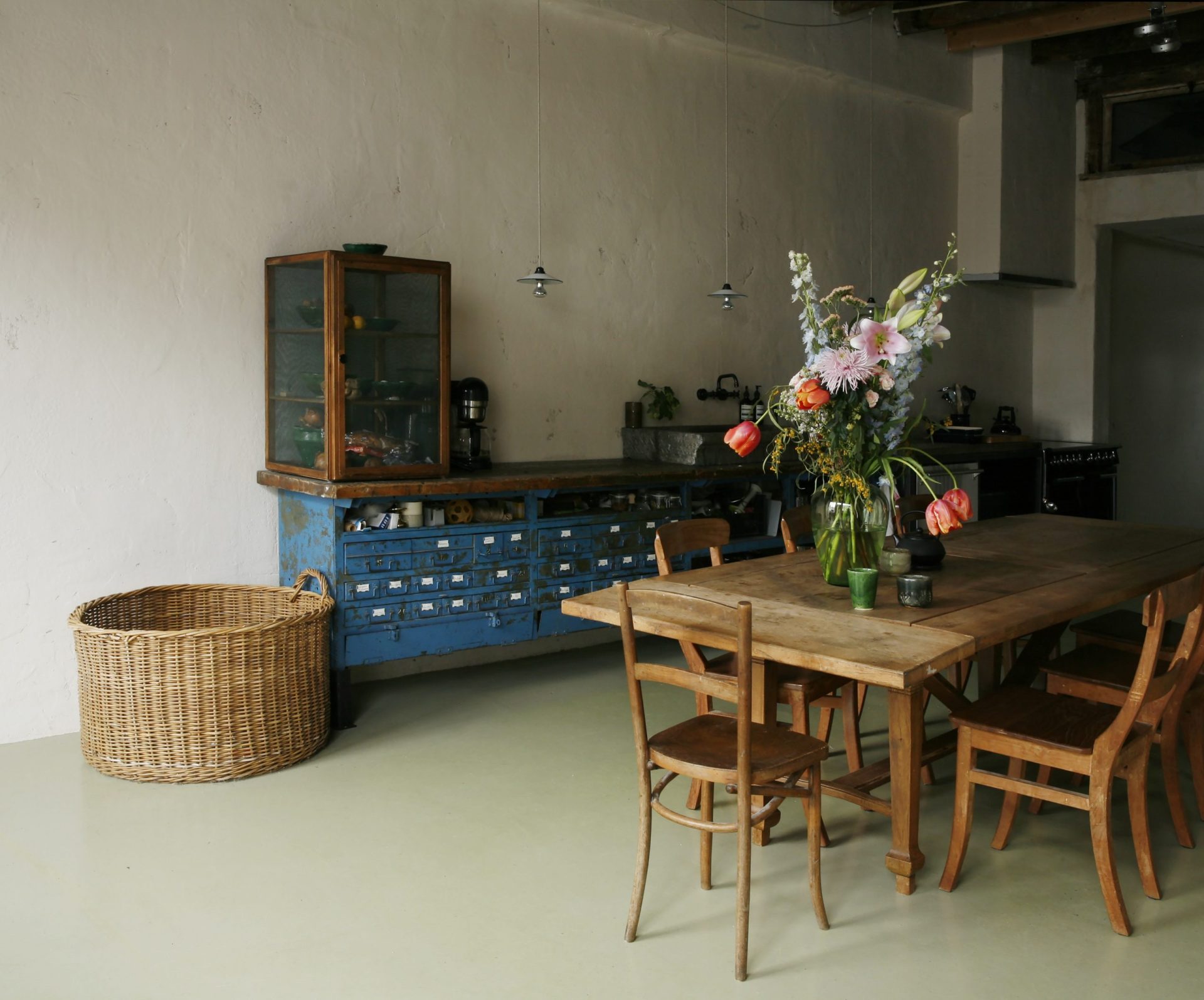 Keuken in robuuste stijl met houten tafel, fornuis, werkbank als aanrecht en lichtgroene marmoleum vloer