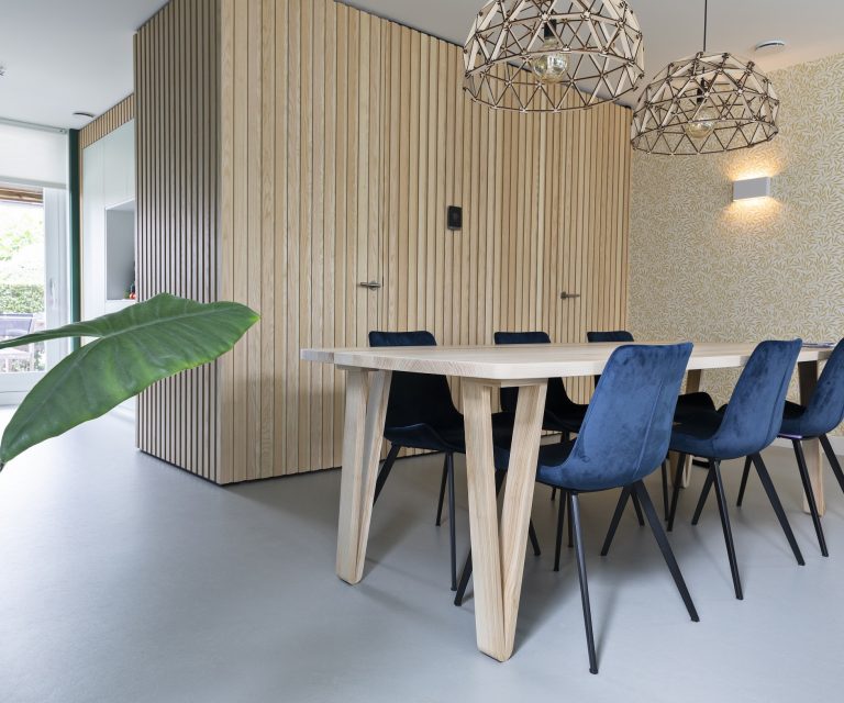 Keuken met houten 6-persoons eettafel, behang met bladpatroon en lichtgrijze marmoleum vloer