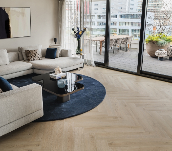 Woonkamer met pvc visgraat vloer in licht eiken, beige hoekbank en moderne salontafel