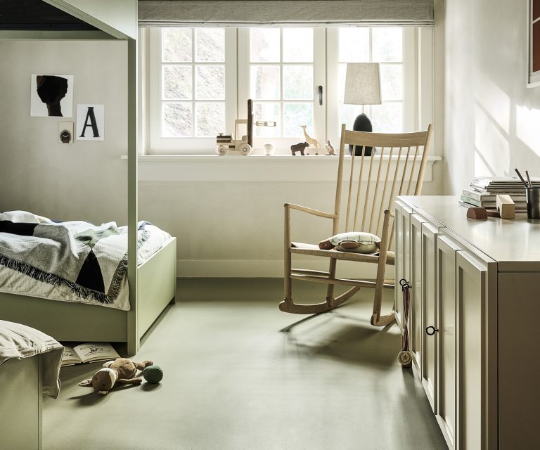 Kinderkamer met beige dressoir, stapelbedden, vouwgordijnen en lichtgroene marmoleum vloer
