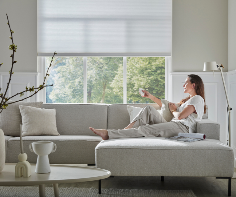 Vrouw op bank met elektrische raamdeco, witte duettes