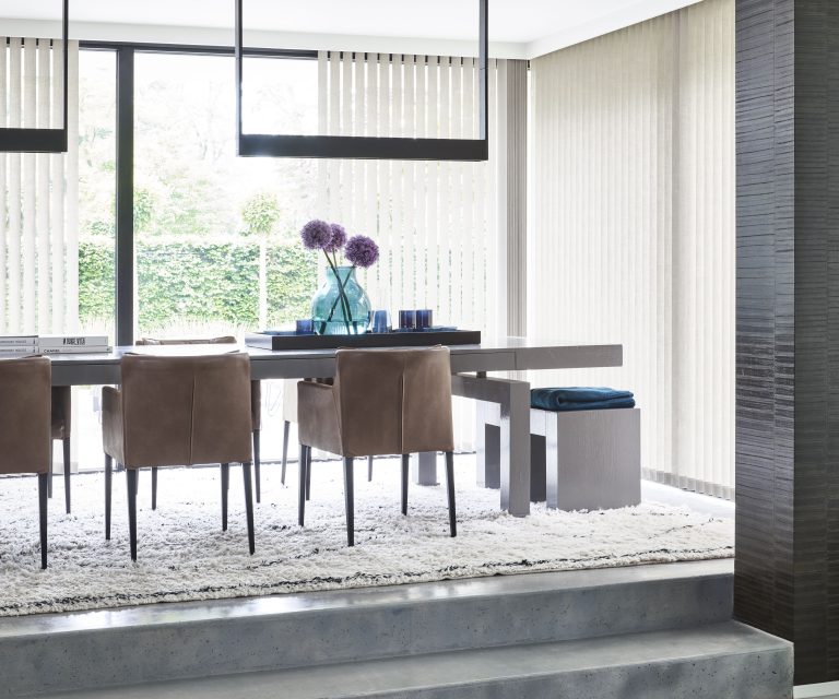 Industriele stijl eetkamer met betonlook vloer en robuuste tafel, lamellen als raamdecoratie