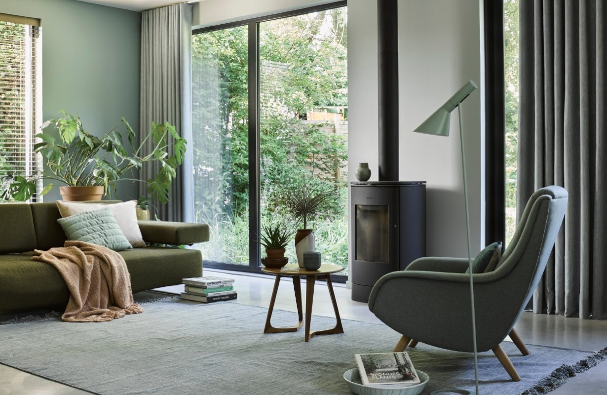 Woonkamer in natuurlijke tinten met kamerhoge gordijnen en zacht vloerkleed.