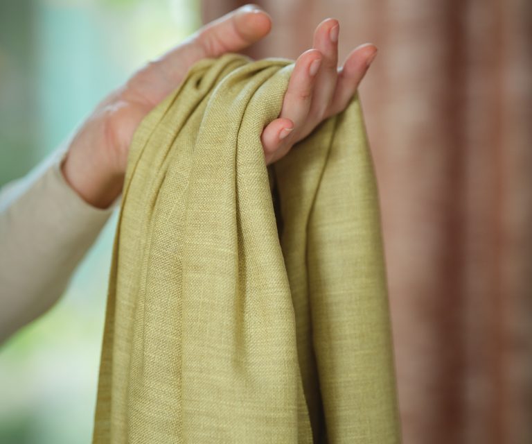 Hand met groene stof voor gordijnen