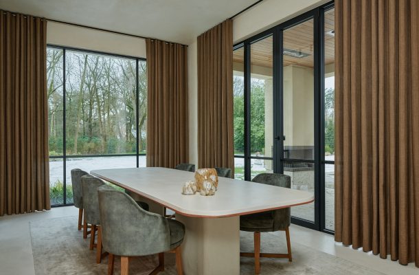 Bruine overgordijnen in eetkamer met tafel, stoelen en licht vloerkleed