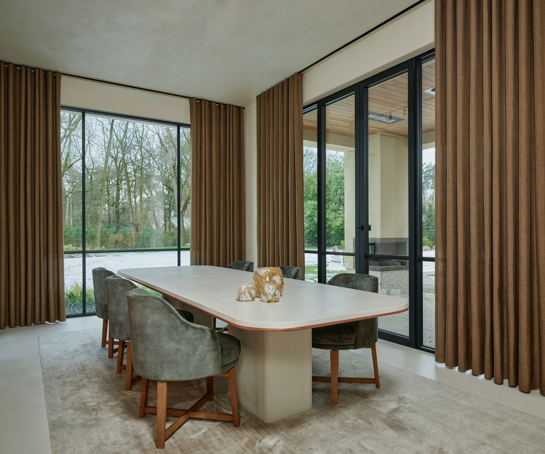 Bruine overgordijnen in eetkamer met tafel, stoelen en licht vloerkleed Bruine overgordijnen in eetkamer met tafel, stoelen en licht vloerkleed