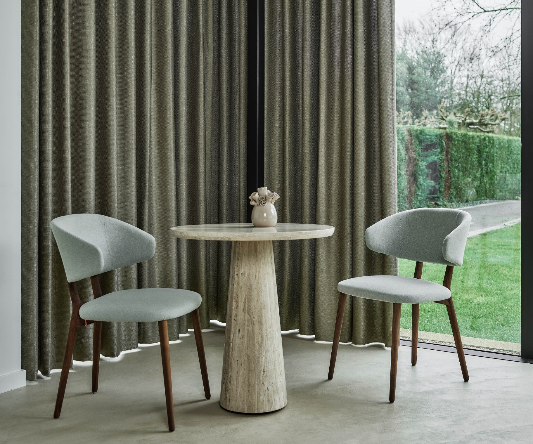 Groene overgordijnen in de zithoek met tafel en twee stoelen Groene overgordijnen in de zithoek met tafel en twee stoelen
