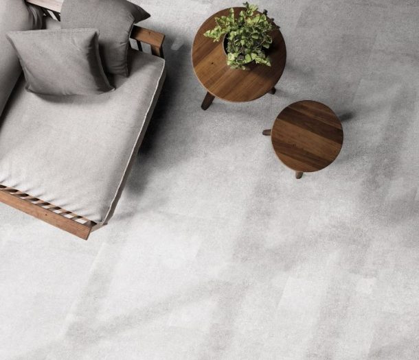 Betonlook pvc-vloer met donkere houten tafeltjes en stoel