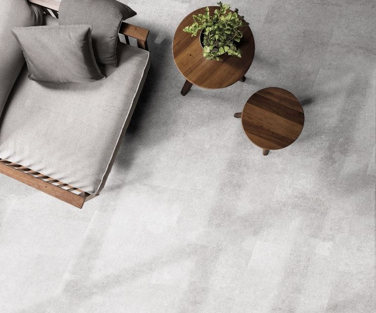 Betonlook pvc-vloer met donkere houten tafeltjes en stoel