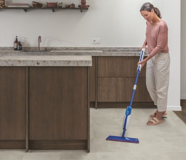 Een betonlook pvc-vloer in de keuken met vrouw die dweilt