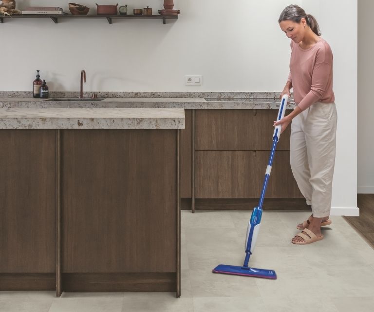 Een betonlook pvc-vloer in de keuken met vrouw die dweilt