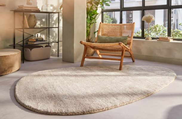 Woonkamer met gietvloer en zacht Brinker vloerkleed in organische vorm