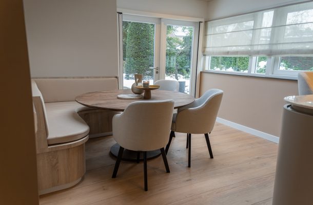 Eetkamer met ronde eettafel en lichte pvc vloer met brede planken