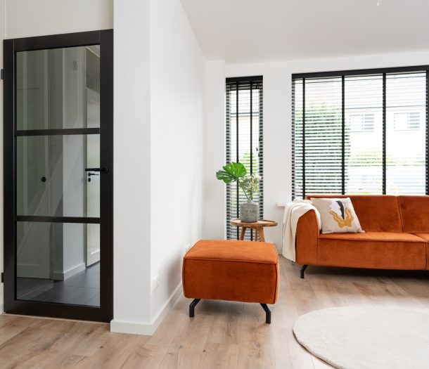 Zwarte binnendeur met glas van woonkamer naar hal