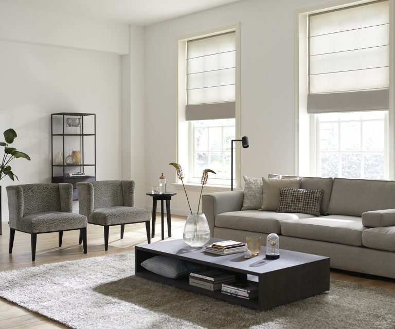 Woonkamer met bank in beige, rechthoekig vloerkleed en vouwgordijnen