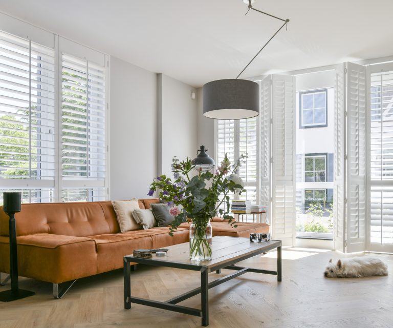 Woonkamer met witte houten shuters van Blend voor deuren en ramen