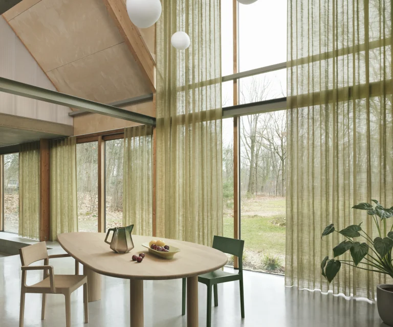 Groene Artex inbetweens voor een hoge glazen wand in een eetkamer met houten tafel